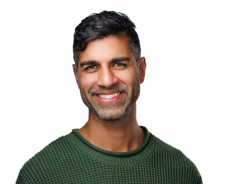 Khurram Naik smiling in a green sweater against a white background