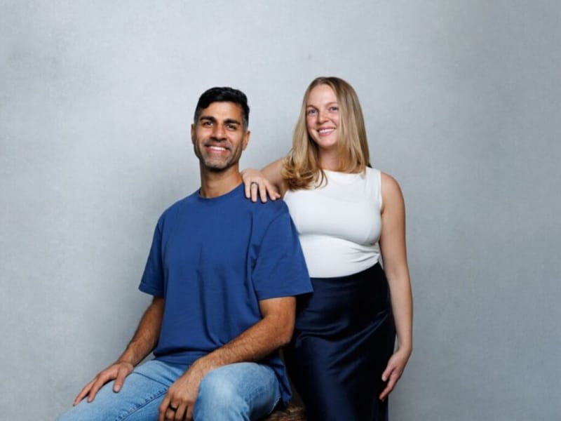 Khurram Naik and Emma seated together against a grey background